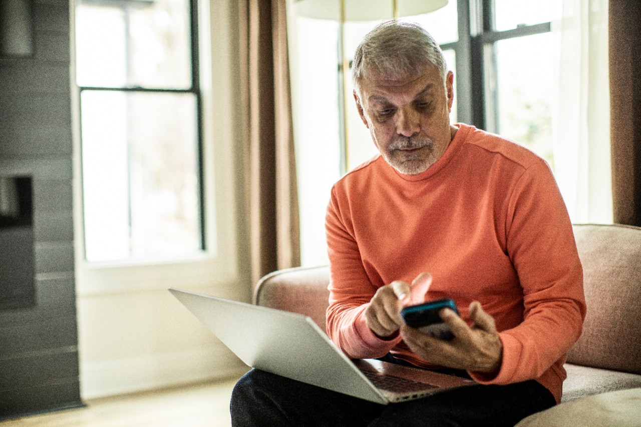 NatWest investments man sitting on sofa using his laptop and app